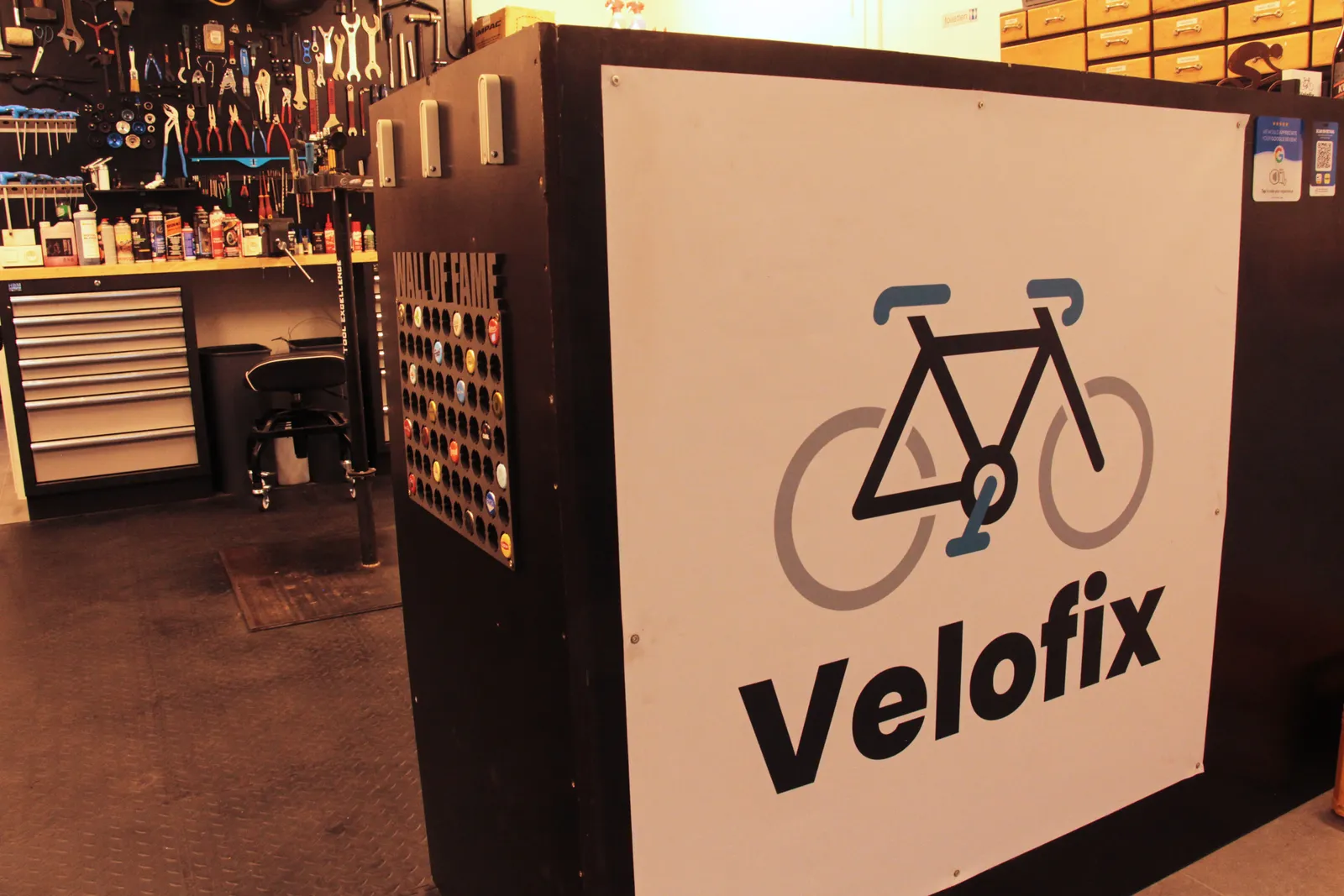 De toonbank van Velofix met het logo, en de gereedschapswand op de achtergrond