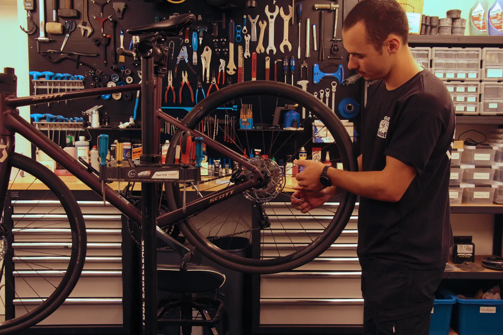Mauro aan het werk aan een fiets in het montagestandaard, met de gereedschapswand erachter